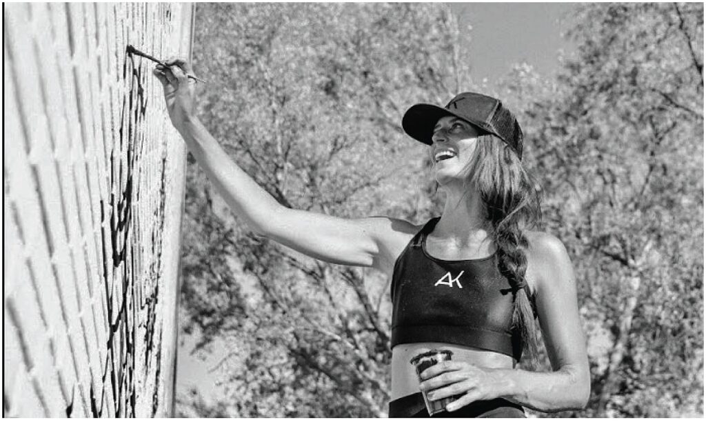 Dallas mural artist Alli K Design painting on a brick wall